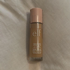 e.l.f. Halo Glow Liquid Filter Light - e.l.f. Halo Glow Liquid Filter i färgen Shade 2 Fair/Light. Ger en glowig finish och kan användas som primer, highlighter eller blandas med foundation. Kommer i en glasflaska med roséguldfärgat lock och innehåller 31,5 ml.