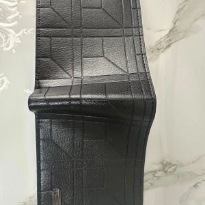 Svart plånbok  - Snygg svart plånbok med geometriskt mönster i skinnimitation. Plånboken har flera fack för kort och ett transparent fönster för ID eller körkort. Stilren design som passar perfekt i fickan eller väskan.