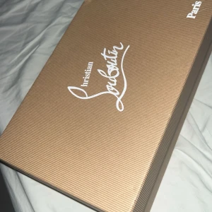 Christian Louboutin skokartong & dustbag - Säljer en original skokartong från Christian Louboutin med tillhörande vit dustbag med röd logga och tillbehör som kvitto och papper. Perfekt för dig som vill ha en snygg förvaring till dina Louboutin-skor eller behöver ersätta din gamla kartong.