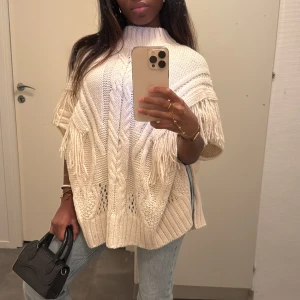 Stickad polotröja med fransar - Beige stickad tröja med grov kabelstickning och fransdetaljer längs sidorna och framtill. Tröjan har en hög polokrage och är kortärmad med loose passform 🎀🤍
