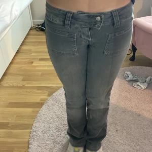 Gråa bootcut jeans  - Snygga gråa jeans med bootcut passform och stora framfickor. Jeansen har en låg midja och klassiska bakfickor.  