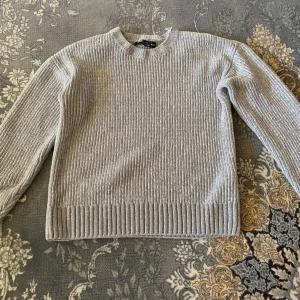 Grå ribbad stickad tröja H&M - Säljer en grå stickad tröja från H&M i storlek XS. Tröjan har ett ribbat mönster, rund halsringning och långa ärmar. Perfekt för lager-på-lager och enkel att matcha med jeans eller kjol.