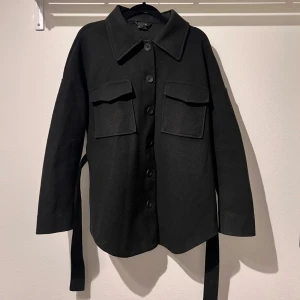 Kort kappa - Svart kort kappa med knappar och bälte i midjan. Lite tunnare som passar perfekt nu till våren. Från Ginatricot, storlek XS. Köparen står för frakten 🩷 