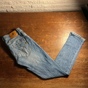 Ljusblå jeans från Dondup - W30 L32. OBS! ena fickan har hål! Säljer ett par ljusblå jeans från Dondup med klassisk femficksdesign och snygga slitningar. Jeansen har raka ben och en snygg läderpatch med logga bak i midjan. Perfekta för dig som gillar en avslappnad och stilren look.