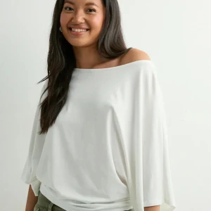 Vit offshoulder topp med vida ärmar - Säljer en vit offshoulder topp med lös passform och vida trekvartsärmar. Toppen har en snygg drapering och faller mjukt över axeln för en chill och trendig look. Perfekt att styla med jeans eller kjol för en avslappnad vibe.