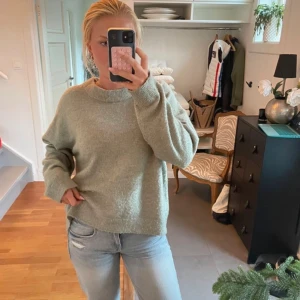 Ljusgrön stickad tröja från H&M - Mysig ljusgrå stickad tröja från H&M i storlek M. Tröjan har en avslappnad passform, rund halsringning och långa ärmar. Perfekt att slänga på sig när det är kyligt ute. Enkel och stilren design som funkar till det mesta.