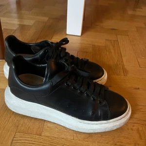 Svarta Alexander McQueen sneakers - Säljer ett par svarta Alexander McQueen sneakers med chunky vit sula och svarta skosnören. Skorna är i skinn och har rund tå samt diskret logga på häl och plös. Perfekta för dig som gillar stilrena och trendiga sneakers med extra höjd. Finns flera bilder 🖤