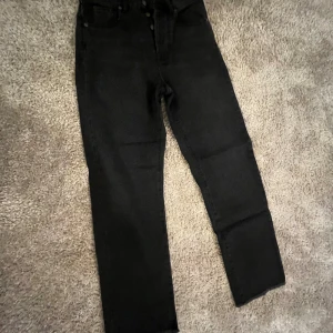 Svarta jeans från By Malina - Snygga svarta jeans från By Malina med klassisk femficksdesign och raka ben. Jeansen har hög midja och är tillverkade i ett robust jeanstyg som ger en stilren look. Perfekta för dig som gillar en enkel men trendig stil.