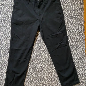 Svarta loose fit byxor Only & Sons - Svarta byxor från Only & Sons i loose fit-modell. Klassisk design med bälteshällor, knapp och dragkedja fram samt fickor både fram och bak. Tillverkade i bomull och polyester för en skön känsla och snygg look. Endast använda vid ett tillfälle, så nyskick. En svart byxa är ett måste i basgarderoben.