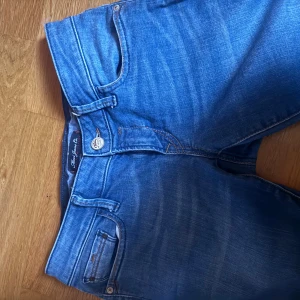 Blå bootcut jeans från True Jeans Co - Snygga blå jeans från True Jeans Co med klassisk bootcut-passform. Jeansen har fem fickor, orange kontrastsömmar och en cool tvättad look. Tillverkade i mjukt denimtyg som sitter skönt hela dagen.