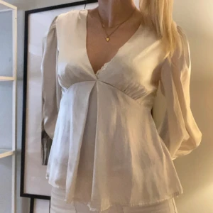 Champagnefärgad blus med v-ringning - Säljer en champagnefärgad satin blus med v-ringning och vida armar. Den har en liten liten skråma vid sidan från förra ägaren då jag köpt den på vinted, men absolut inget som märks av🥰