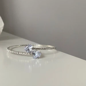 Caroline Svedbom liknande armband - Snyggt och glittrigt armband i silverfärg med små gnistrande stenar längs hela bandet och två större hjärtformade kristaller framtill.  Ca 18 cm runt handleden och helt oanvänt.                                            Det är inte Caroline Svedbom, men likt ‼️