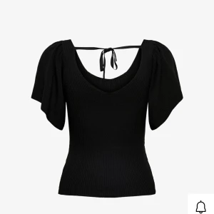 Svart ribbad topp med knyt från ONLY - Supersnygg svart ribbad topp från ONLY med v-ringning, korta vida ärmar och knyt i ryggen. Toppen har en figurnära passform och är tillverkad i stretchigt material som sitter bekvämt. Perfekt att styla med jeans eller kjol för en trendig look. Använd några enstaka gånger men inga fläckar eller hål!❣️säljer likadan i vit!🤞🏻