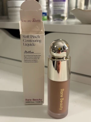 Rare Beauty Soft Pinch Contour Mellow - Rare Beauty Soft Pinch Contouring Liquid i färgen Mellow. Flytande bronzer med lätt formula som är enkel att blenda för en naturligt skulpterad look. 
