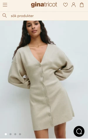 Beige kort klänning - Säljer en beige kort klänning från Gina Tricot med v-ringning och långa ärmar. Klänningen har knappar hela vägen framtill och är gjord i ett mjukt stickat material.