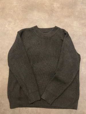Grå stickad tröja Maison Margiela - Säljer en grå stickad tröja från Maison Margiela med klassisk rund hals och ribbade muddar. Den är i storlek S och är väldigt tjock och håller dig varm.   Axel till axel mått: 42 cm  Längden på hela tröjan: 63cm 