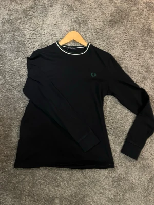 Svart långärmad topp från Fred Perry - Svart långärmad topp från Fred Perry med rund halsringning som har vita och gröna ränder. Storlek S och passar dig som är ca 170-180. Jättefint skick. mvh