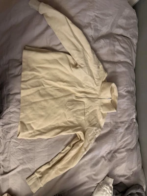 Beige tröja med half zip - Mjuk och skön beige tröja i storlek M med lång ärm och hög krage. Tröjan har en praktisk half zip framtill och en liten bröstficka. Perfekt för kyliga dagar när du vill vara både bekväm och stilren.