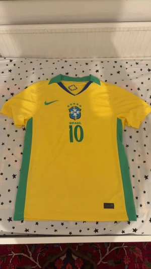Brasilien Jersey med Neymar 10  - Bilderna visar en gul Brasilien fotbollströja med gröna detaljer och nummer 10, Neymar Jr, Fin för sommaren och skön för träning.
