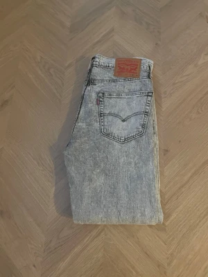 Levi's 501 ljusgrå jeans - Säljer ett par klassiska Levi's 501 jeans i ljusgrå tvättad denim. Modellen är slim tapered . Snyggt slitna detaljer och ikonisk läderpatch bak i midjan. Storlek L32 M30