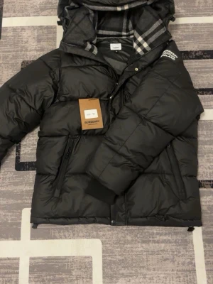 pufferjacka från Burberry - Säljer en svart pufferjacka från burrbery. Perfekt nu inför kalla dagar. Riktigt bra passform helt ny.