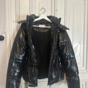 Svart pufferjacka från Nelly XS - Svart pufferjacka från Nelly i glansigt material. Inga teckna på användning!