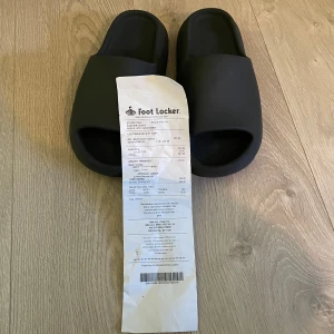 Adidas Yeezy Slides - Köpte dem för  1 år sen på footlocker i Brooklyn och de passar inte mig längre. Jag köpte dem nya för 2200 kr utan moms och har använt dem typ i 3 veckor tills jag gick ur dem. Har tyvärr inte kvar boxen , därför är priset sänkt drastisk men har kvitto 🧾 Fråga hjärna frågor som du funderar över 😊