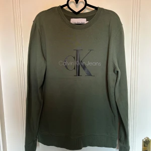 Olivgrön sweatshirt från Calvin Klein - Olivgrön sweatshirt från Calvin Klein Jeans med stor CK-logga framtill. Den är i storlek L. 