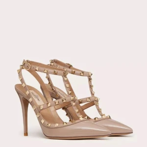 Valentino Rockstud pumps i beige lack - Säljer ett par ikoniska Valentino Rockstud pumps i beige lackat skinn med spetsig tå och hög klack. Skorna har remmar dekorerade med guldiga nitar och justerbart spänne vid ankeln. Perfekta för dig som vill sticka ut med en edgy men lyxig look.