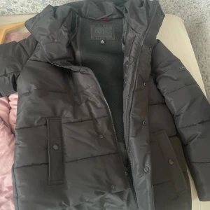 Michael Kors jacka - Michael Kors jacka som är helt oanvänd och är köpt i butik. Perfekt för dig som vill hålla dig varm under dom kallare dagarna då denna absolut gör jobbet. Lapparna tog jag av då jag hade tänkt använda den men aldrig gjorde det, så den är som sagt helt ny. Jackan är vattenavvisande och vindtät, har dragkedja och tryckknappar framtill.