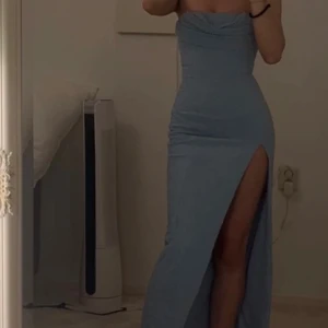 Ljusblå långklänning Oh Polly med slits - Supersnygg ljusblå långklänning från Oh Polly med pärlbroderier över hela tyget. Klänningen är axelbandslös, har en hög slits på ena benet och en figurnära passform. Perfekt för dig som vill sticka ut med en elegant look. Använt 1 gång 