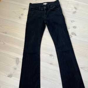 Svarta lågmidjade bootcut jeans  - Svarta lågmidjade jeans med bootcut-modell och snygga bakfickor med lock och knappdetalj. Är i storlek 164 men passar mig som har 34/36💕från Gina tricot 