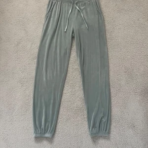 Grön mjukisbyxor med snörning - Mysiga gröna mjukisbyxor med resår och snörning i midjan. Byxorna har fickor på sidorna och resår vid bensluten. Tillverkade i ett mjukt och lent material som känns skönt mot huden. Perfekta för chill dagar hemma eller när du vill vara extra bekväm.