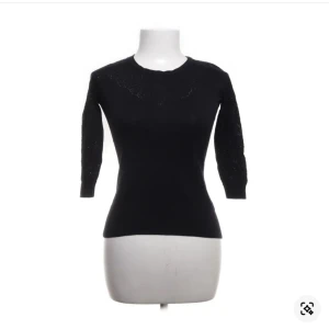 Svart stickad tröja med glitterdetaljer - Snygg svart stickad tröja med glittriga detaljer vid halsringningen och på ärmarna. Modellen är figurnära med trekvartsärm och rund hals. Perfekt för dig som vill ha en stilren men ändå lite extra look.