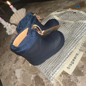 Mörkblå fodrade gummistövlar från Bisgaard - Snygga mörkblå gummistövlar som är fodrade  från Bisgaard med justerbar dragsko upptill i blått tyg och detaljer i läder. Perfekta för regniga dagar och lek utomhus. Kommer med praktisk förvaringspåse. 