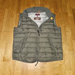 Parajumpers Dunväst - Snygg olivgrön dunväst från Parajumpers i superlätt material. Västen har quiltad design, dragkedja framtill och två fickor med dragkedja. Perfekt för lager-på-lager och har en stilren look med diskreta detaljer och hög krage. Priset kan diskuteras och om man köper samma dag så fraktar jag samma dag.