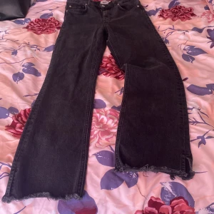 Svarta wide jeans med råa kanter - Säljer ett par svarta jeans i storlek M med hög midja och breda ben. Jeansen har råa, fransiga kanter nertill för en cool och avslappnad vibe. Perfekta för dig som gillar en trendig och bekväm stil. Kan tänka mig att förhandla priset. 