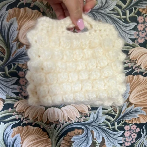 Handgjord stickad vit handväska - Supersöt handgjord virkad handväska i fluffigt vitt garn. Väskan har ett bubbligt mönster och ett litet handtag upptill. Perfekt accessoar för dig som vill ha något unikt 💕höjd 13, bredd 16