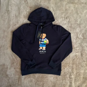 Brun hoodie Polo Ralph Lauren björn - Det Polo Ralph Lauren Hoodie – Bear Edition Snygg marinblå hoodie från Polo Ralph Lauren mjukt och skönt material.