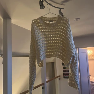 Vit stickad tröja från Stradivarius - Säljer en vit stickad tröja från Stradivarius med grovt virkat mönster och ribbade muddar. Tröjan har lång ärm och är lite croppad framtill, perfekt för lager-på-lager. Superfin till jeans eller kjol!