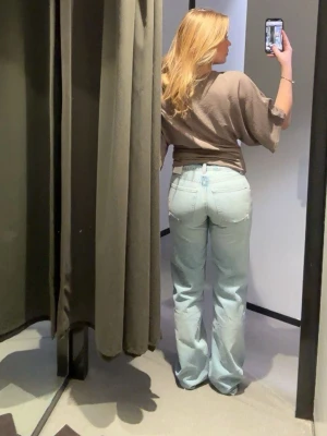 Ljusblå raka jeans med normal midja - Säljer ett par ljusblå jeans med klassisk femficksdesign och raka ben. Jeansen har normal midja och är tillverkade i mjukt denimtyg. Perfekta för en avslappnad och trendig look.