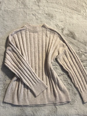 Beige ribbad stickad tröja - Stickad tröja med breda ribbade ränder och rund hals. Supermjuk och skön mot huden. Endast testad 
