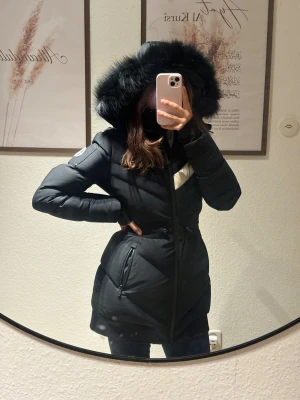 Moose Knuckles Limited Edition  - Svart dunjacka från Moose Knuckles med en vit detalj över bröstet och loggan på vänster ärm. Jackan har en avtagbar huva med svart päls. Den har även en dragkedja framtill och fickor med dragkedja på sidorna.  Jackan är använd max 3 gånger med andra ord jackan är i princip nyskick, inga skador eller märken alls! Köptes från thernlunds i Stockholm för 13 799kr. Kvitto finns. Storlek: XS