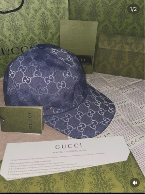 Blå mönstrad keps - Snygg blå keps med det klassiska GG-mönstret över hela plagget. Västen har en modern passform och är tillverkad i ett slitstarkt syntetmaterial som ger en lyxig känsla. Perfekt för dig som vill sticka ut med exklusiv design och ikoniskt mönster.