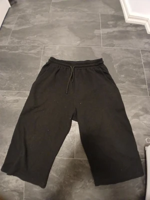 Svarta loose shorts med snörning - Svarta shorts i loose fit med breda ben och elastisk midja med snörning. Mjukt material som känns skönt mot huden, perfekta för chill dagar. Enkla att matcha med allt och ger en avslappnad vibe.