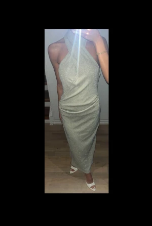 Glittrig Halterneck Silver Festklänning  - Säljer en Silver glittrig halterneck festklänning. Klänningen är skydd hos skräddaren för en mer figursydd fit samt insydda inlägg. Funkar perfekt till festliga tillfällen!!🥰