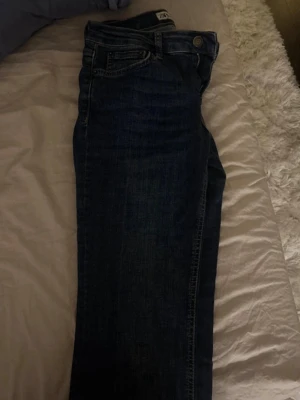 Blå jeans från Zara - Snygga blå jeans från Zara i klassisk femficksmodell med raka ben och normal passform. Jeansen har en mörkblå tvätt och är tillverkade i slitstarkt denimmaterial. Perfekta för dig som gillar enkel och tidlös stil.