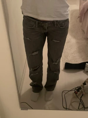 Grå slitna jeans med raka ben - Säljer ett par grå jeans med flera slitningar och hål på benen. As snygga och Lågmidjade, skriv för mått 💕