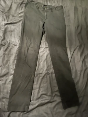 Svarta chinos från J.Lindeberg - Säljer ett par svarta chinos från J.Lindeberg i storlek 31/34. Byxorna har raka ben, bälteshällor och två bakfickor med knappstängning. Materialet är mjukt och känns som bomull, perfekt för en clean och stilren look.