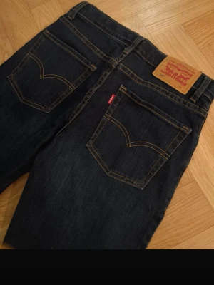 Levi's 510 Skinny mörkblå jeans - Säljer ett par Levi's 510 Skinny jeans i mörkblå tvätt med klassiska kontrastsömmar och fem fickor. Modellen har smal passform och låg midja, tillverkade i slitstarkt jeansmaterial. Perfekt för dig som gillar en tajt look och vill ha ett stilrent basplagg.